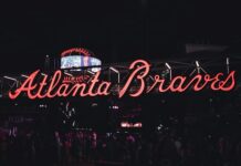 Neon Atlanta Braves sign glowing at night with visitors walking underneath.