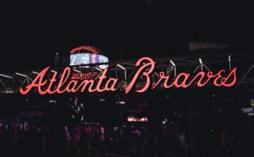 Neon Atlanta Braves sign glowing at night with visitors walking underneath.