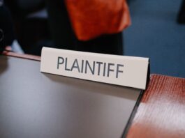 Coinbase Sues Illinois, Michigan, and Connecticut Over Prediction Markets as Legal Fight Expands to 10 States Plaintiff nameplate on a courtroom table.