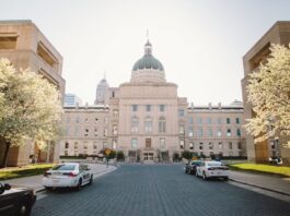 Indiana Bill Targets Online Sweepstakes Casinos With New Definition, $100K Penalties Exterior view of the Indiana Statehouse in Indianapolis with police cars parked in front and spring trees in bloom