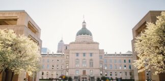 Indiana Bill Targets Online Sweepstakes Casinos With New Definition, $100K Penalties Exterior view of the Indiana Statehouse in Indianapolis with police cars parked in front and spring trees in bloom