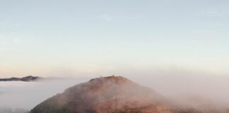 A mountain road dividing into two separate paths on a foggy hillside.