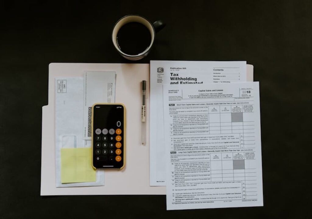 Calculator, tax forms, envelopes, and paperwork arranged on a desk related to U.S. tax filing