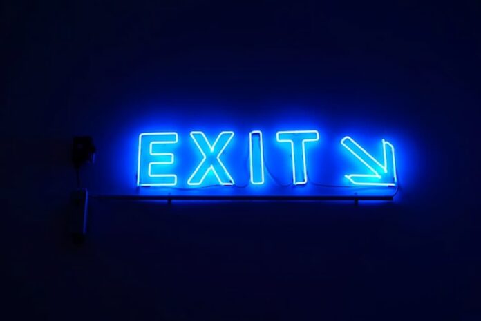 Blue neon “Exit” sign with an arrow pointing right against a dark background