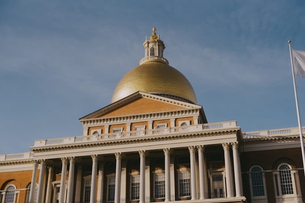 The Massachusetts State House in Boston with its gold dome and columned facade under a clear sky