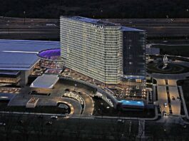Aerial night view of the MGM National Harbor hotel and casino complex with illuminated tower, entrance, and surrounding roads.