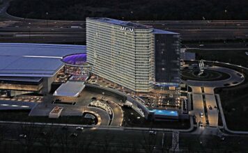 Aerial night view of the MGM National Harbor hotel and casino complex with illuminated tower, entrance, and surrounding roads.