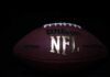 Close-up of an official NFL football on a dark background.