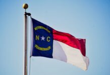 Lumbee Tribe Nears Federal Recognition, Opening Door to Eastern North Carolina Casino North Carolina state flag flying on a flagpole against a clear blue sky