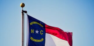 Lumbee Tribe Nears Federal Recognition, Opening Door to Eastern North Carolina Casino North Carolina state flag flying on a flagpole against a clear blue sky