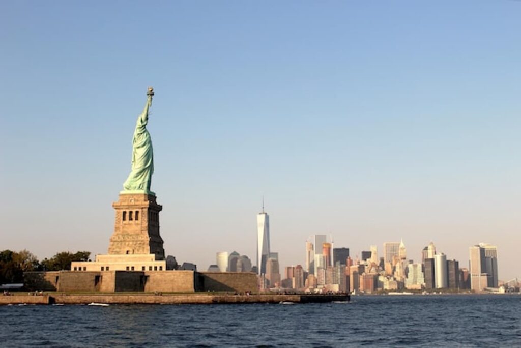 The Statue of Liberty with the Manhattan skyline visible across New York Harbor