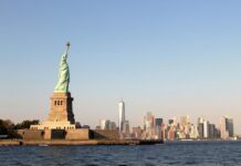 The Statue of Liberty with the Manhattan skyline visible across New York Harbor