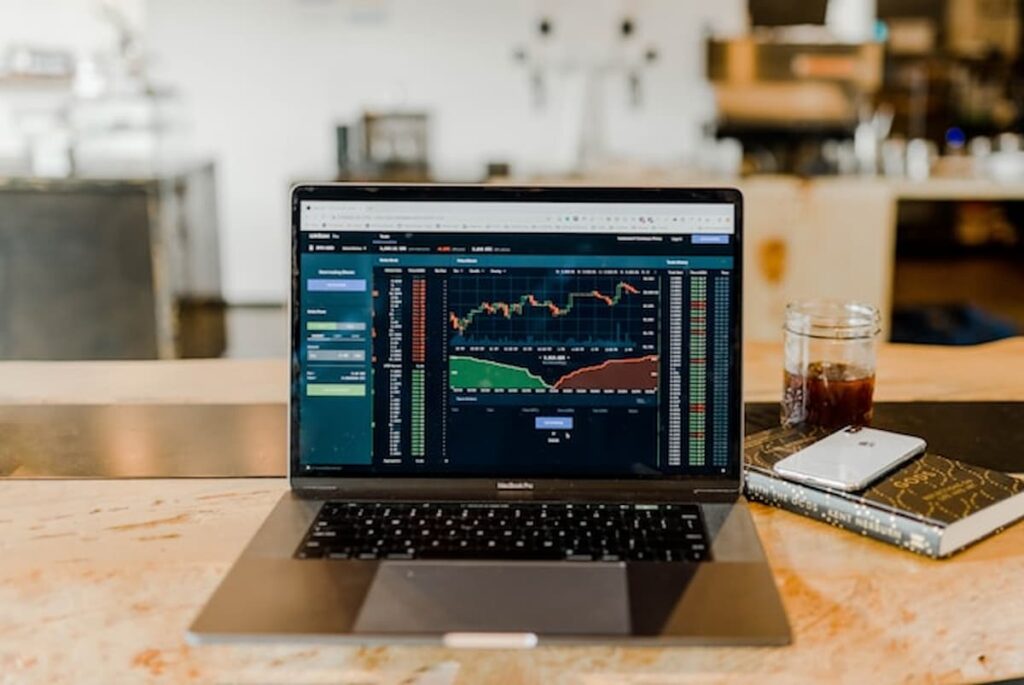 Laptop displaying financial trading charts on a desk