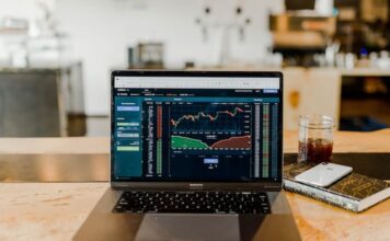 Laptop displaying financial trading charts on a desk