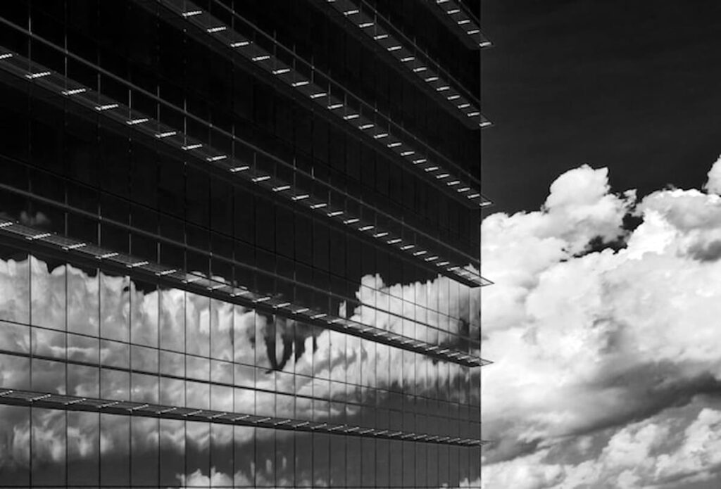 Glass office tower with clouds reflected in the windows