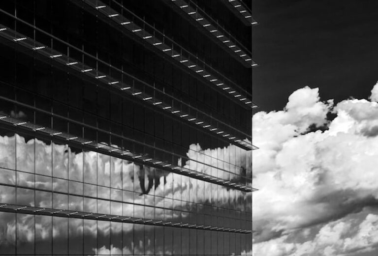Glass office tower with clouds reflected in the windows