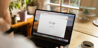 Google Opens Ad Platform to U.S. Prediction Markets A person using a laptop displaying the Google homepage while sitting at a table with a cup of coffee.