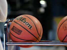 College basketballs resting on a rack courtside during a game