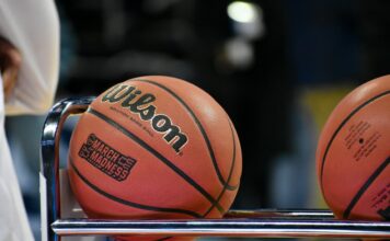College basketballs resting on a rack courtside during a game