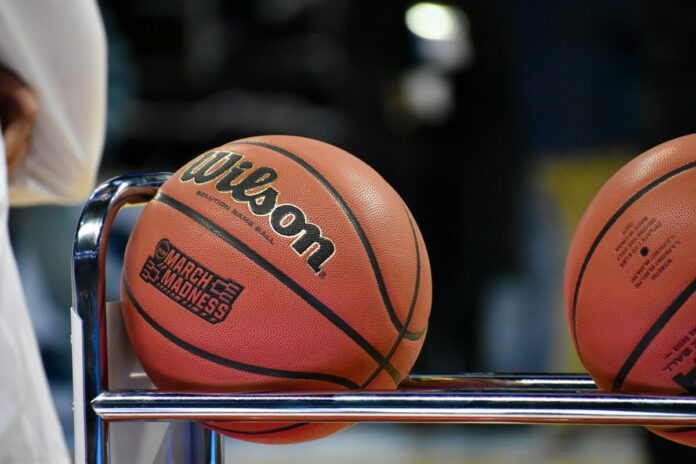 College basketballs resting on a rack courtside during a game