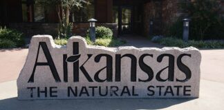 Stone sign reading “Arkansas The Natural State” outside a public building