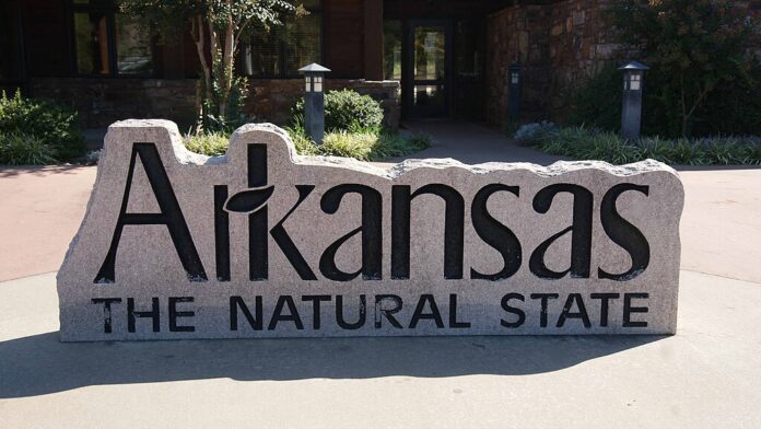Stone sign reading “Arkansas The Natural State” outside a public building