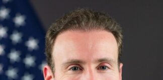 Selig Asserts CFTC Dominance as States Target Prediction Markets Portrait of CFTC Chariman Michael Selig in a suit standing in front of an American flag.