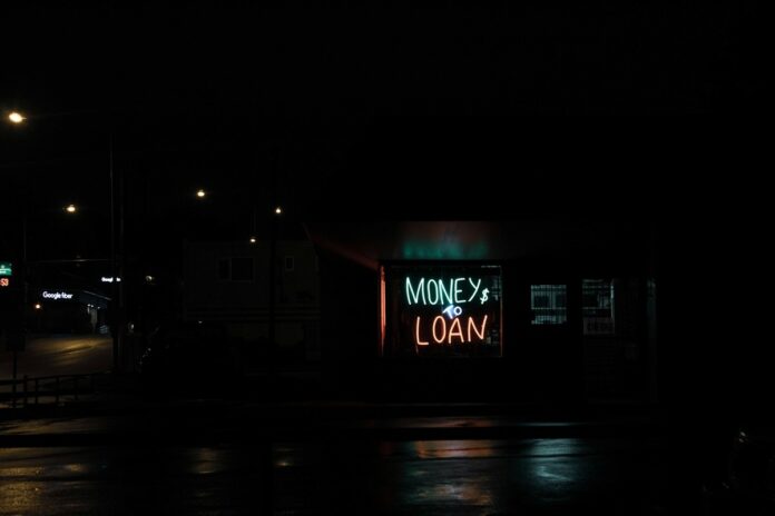 A neon sign in a window that says Money to Loan.