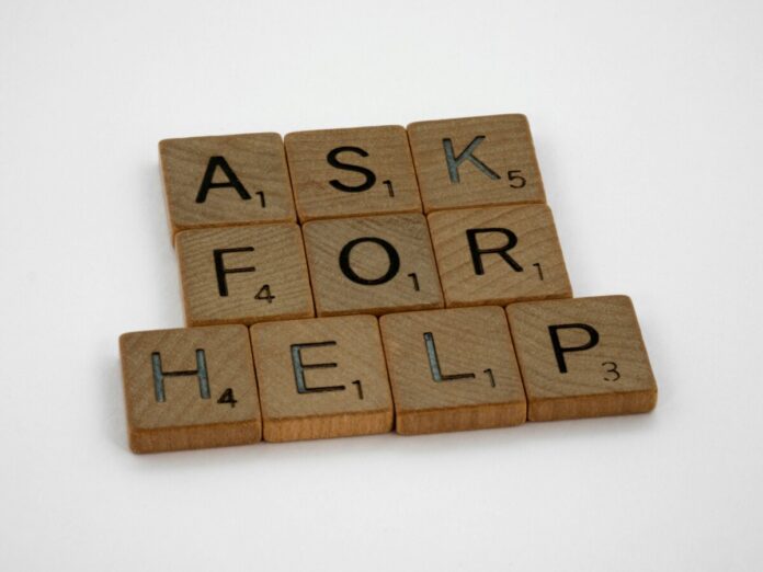 Wooden letter tiles spelling “ask for help” on a white background