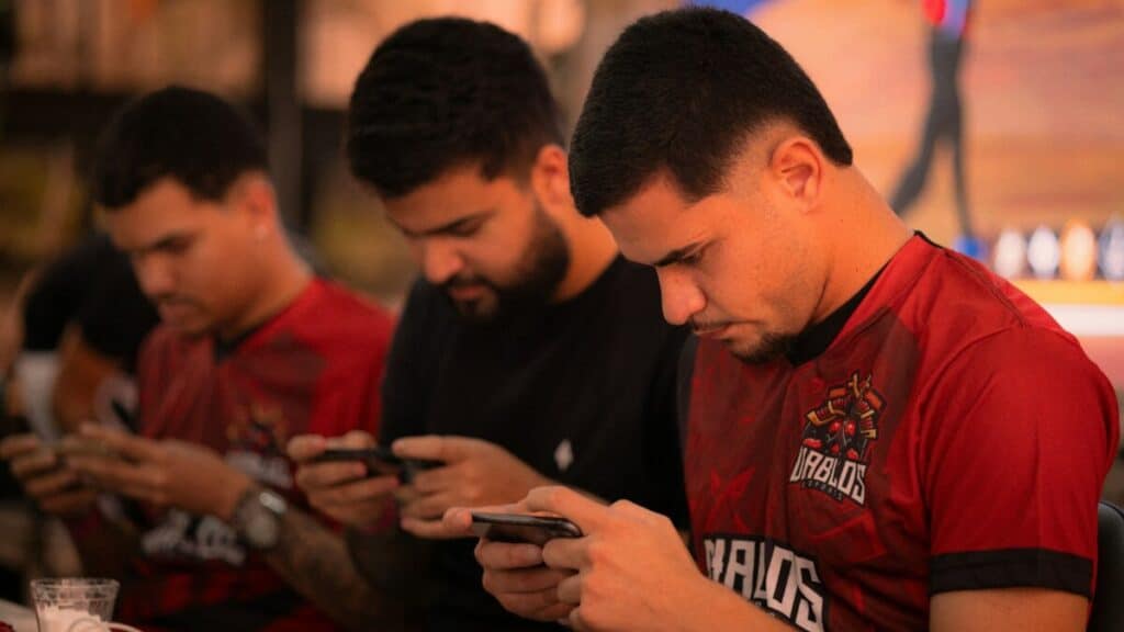 Group of men focused on their smartphones during a live event, illustrating mobile sports betting behavior