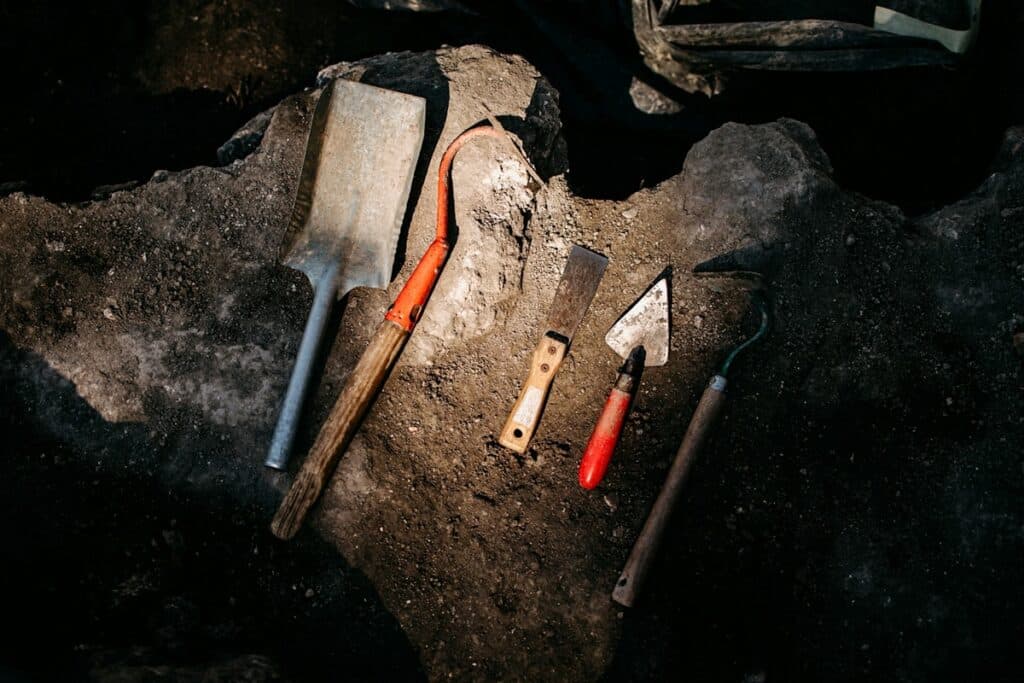 Various tools used for archaeology placed on rocky soil.
