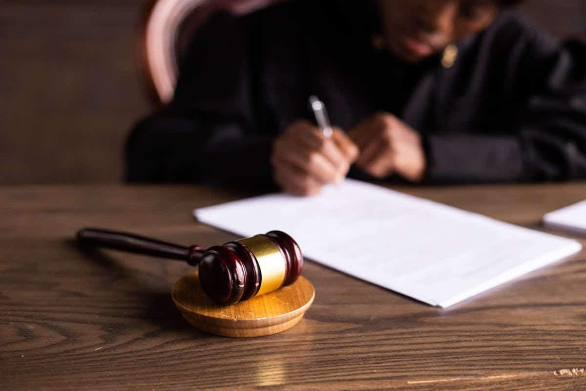 A judge writing on a desk with a gavel in the foreground.